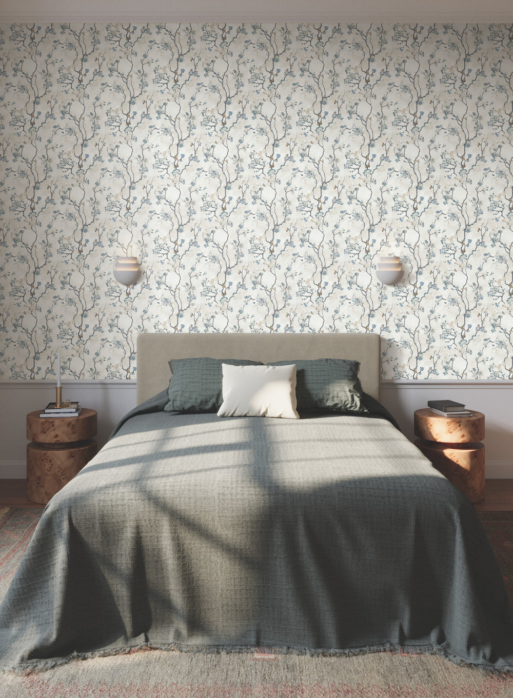 Lemieux et Cie Avril Chinoiserie wallpaper in peacock blue on misty gray, flowering branch motif, bedroom setting with upholstered bed and burl nightstands.