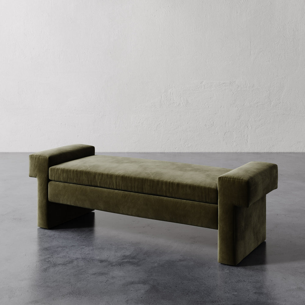 Lemieux et Cie Lemaire Bench in olive green, upholstered bench with sculptural cylindrical bolster arms, shown on concrete floor against white plaster wall.