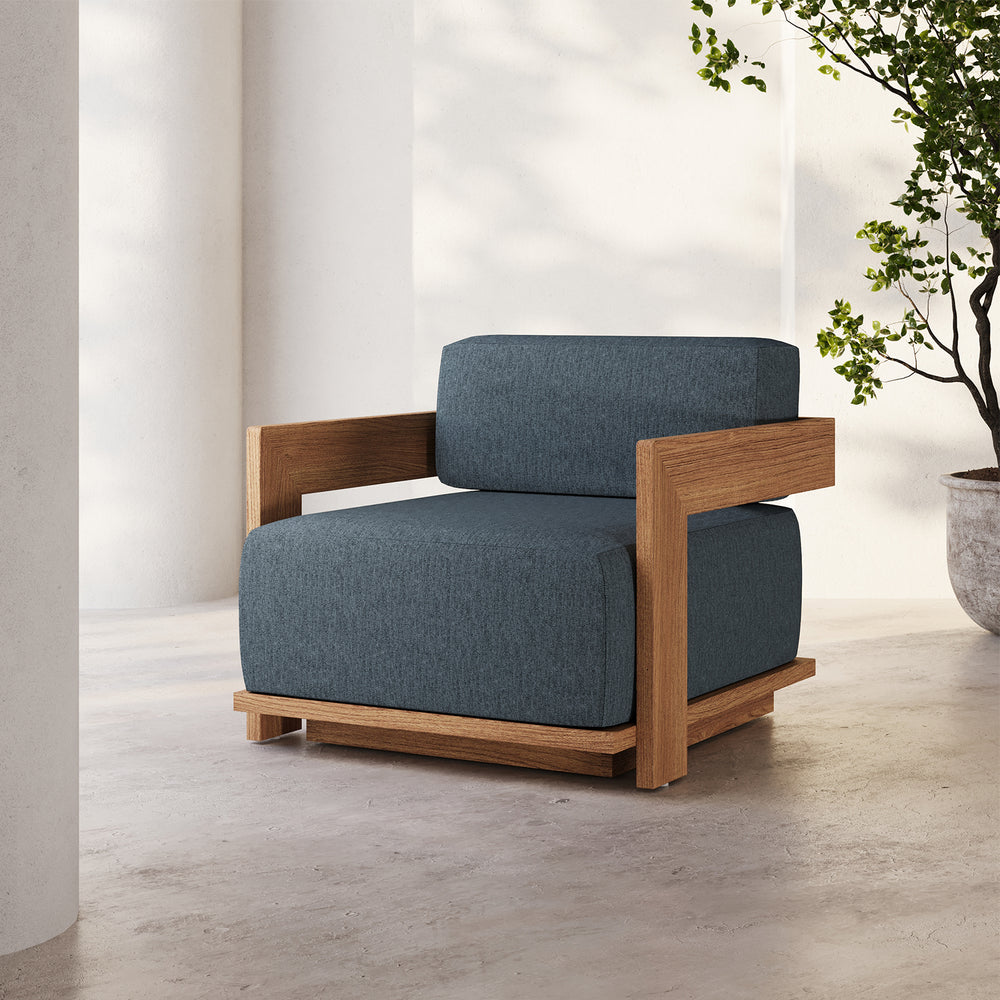 Lemieux et Cie S2 Teak Lounge Chair with dark teal upholstered cushions and warm wood frame, shown on concrete floor against white walls