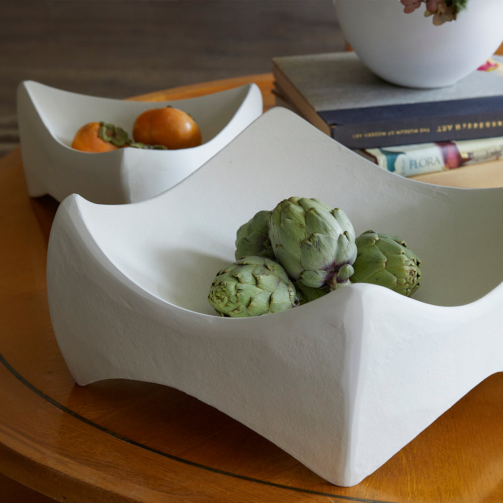 Lemieux et Cie Marius Square Bowl and Léandre Triangle Bowl in white, sculptural ceramic bowls with origami-inspired angular folds, styled with fresh produce on wood dining table.