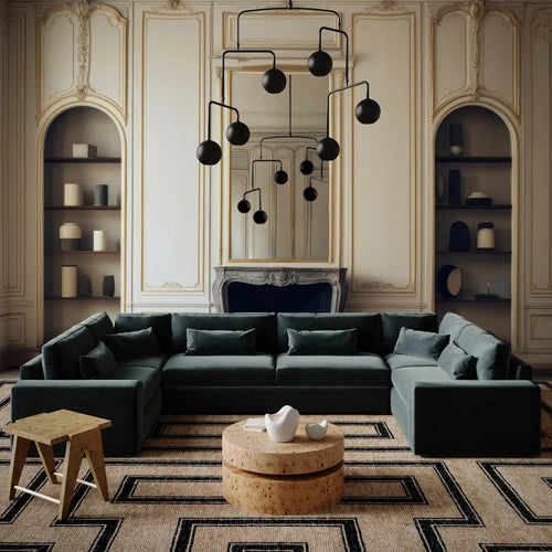 Lemieux et Cie Lacroix U-Sectional in forest green velvet, modular sofa styled in ornate paneled salon with matte black chandelier and arched niches.
