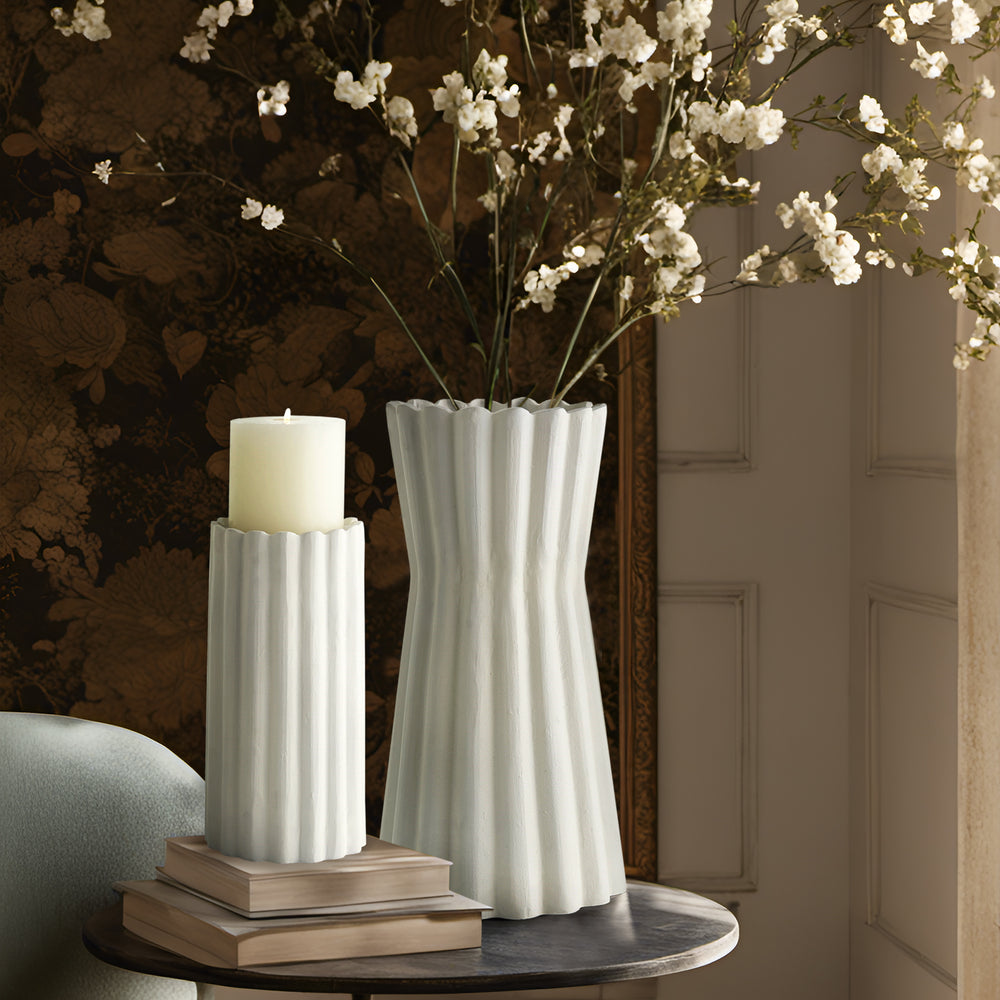 Lemieux et Cie Gaspard Vase in white with fluted sculptural form, styled with candle holder and blooms on dark stone table against neutral paneled walls.