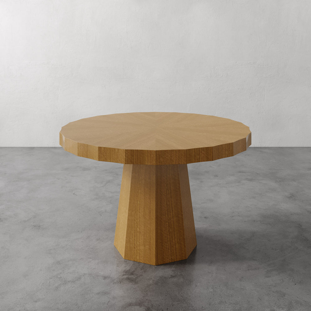 Lemieux et Cie Ondara Fluted Dining Table in champagne eucalyptus with radial marquetry top and fluted pedestal base, shown on concrete floor against white walls.