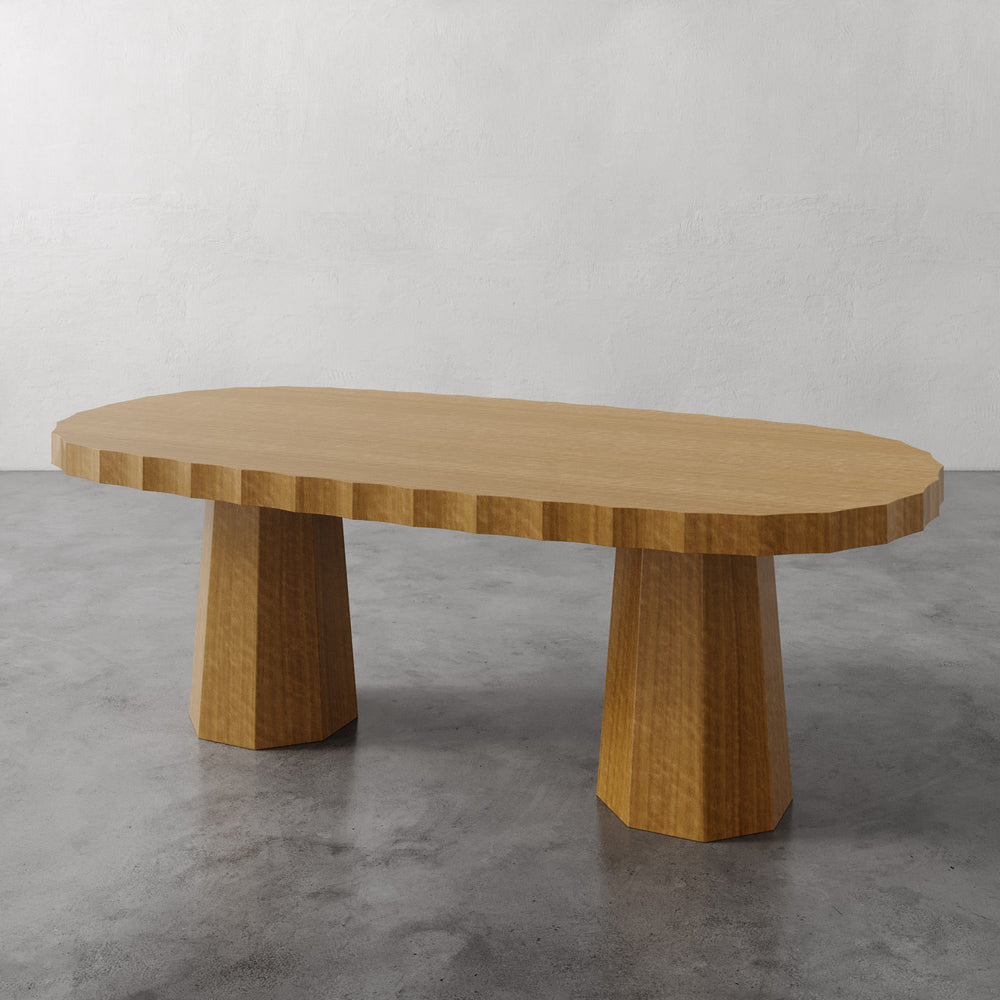Lemieux et Cie Ondara Fluted Dining Table Oblong, low table with sculptural tapered legs on stone floor with white walls.