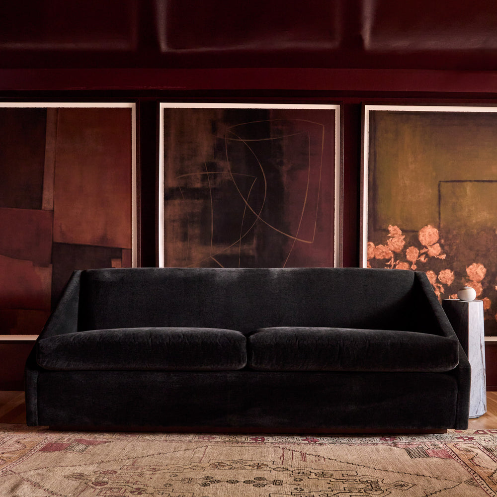 Lemieux et Cie Black Fontaine sofa in a room with abstract art on the wall.