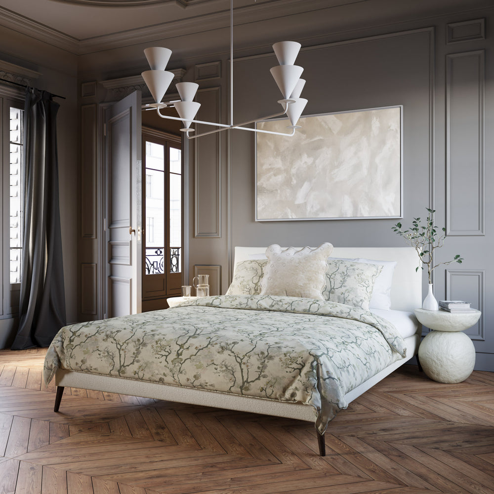 Lemieux et Cie Cornet 4 Light Extra Large Chandelier, a luxury lighting fixture, hangs above a bed with layered bedding in a calm bedroom.