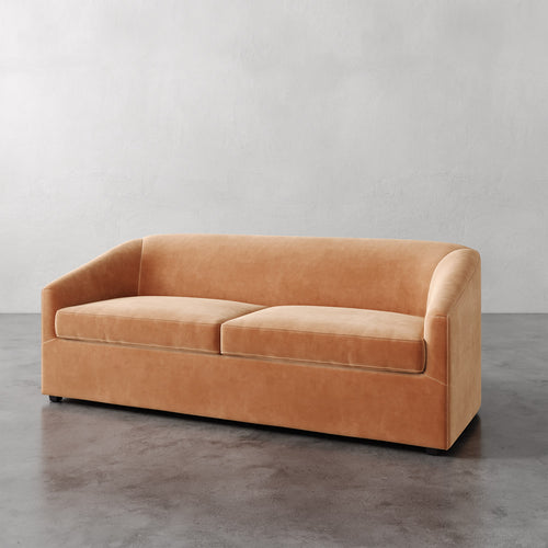 Lemieux et Cie Arvelle Queen Sleeper in warm terracotta, two-cushion sofa with curved arms and low profile, shown on polished concrete floor.
