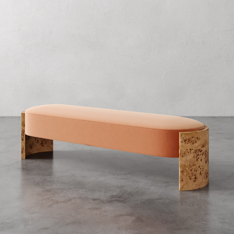 Lemieux et Cie Benoit Custom Upholstered Bench with curved Maple burl legs and blush upholstered seat, shown on concrete floor against textured plaster walls