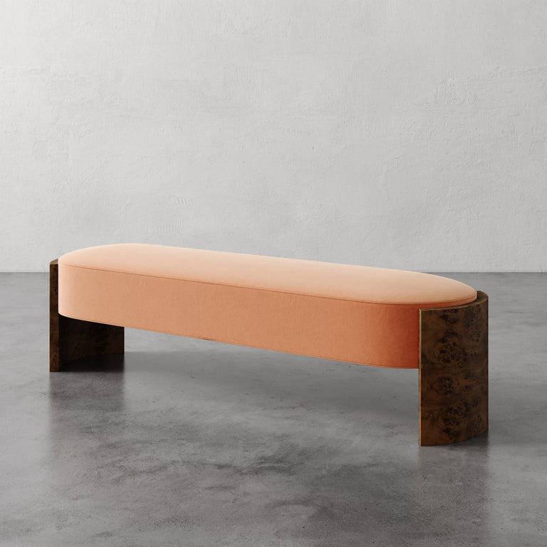 Lemieux et Cie Benoit Bench in blush upholstery with curved Maple burl legs, upholstered bench on polished concrete floor against textured plaster walls.
