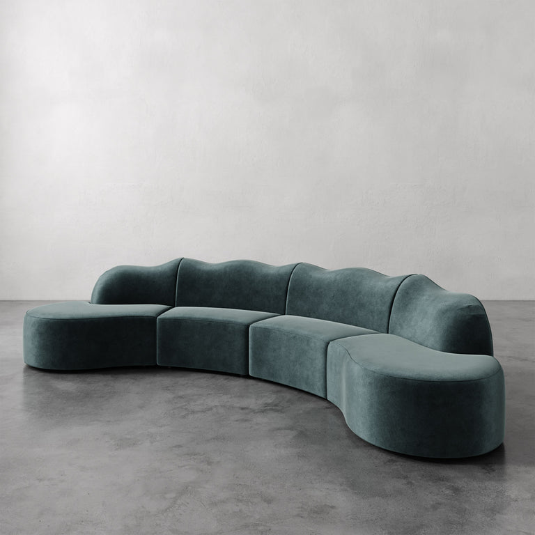 Lemieux et Cie Serpentine Sectional Sofa in sage green, modular seating with rounded organic forms, shown on polished concrete floor against neutral walls.