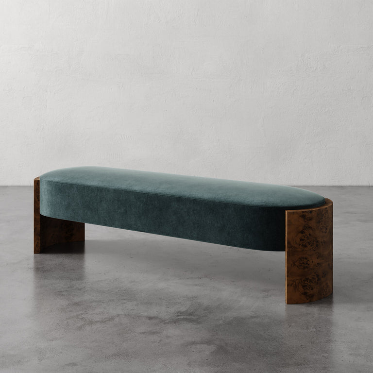 Lemieux et Cie Benoit Custom Upholstered Bench in teal velvet with curved Maple burl legs, shown on polished concrete floor against neutral plaster wall