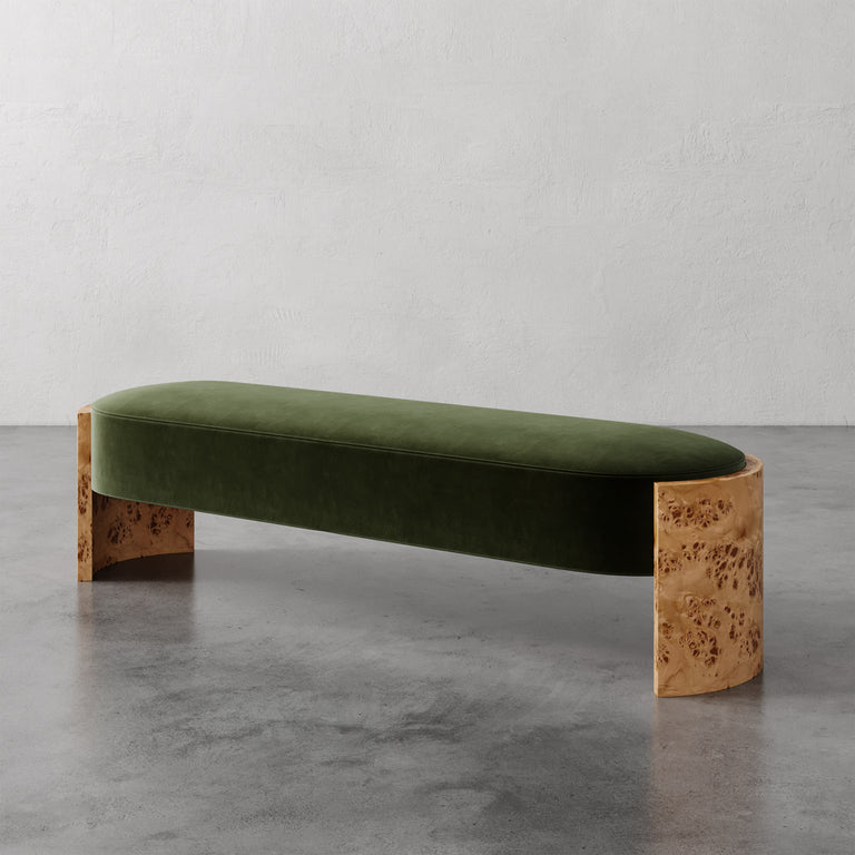 Lemieux et Cie Benoit Custom Upholstered Bench in olive green velvet with curved Maple burl legs, shown on polished concrete floor against textured plaster walls.