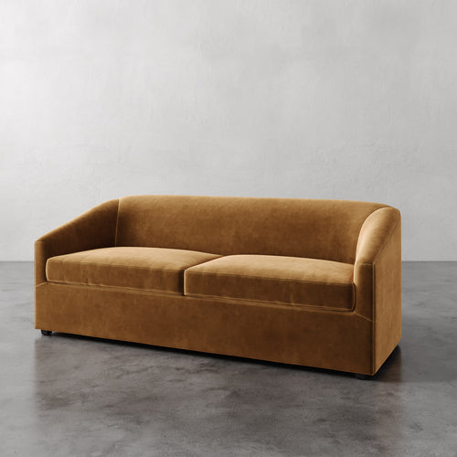 Lemieux et Cie Arvelle Queen Sleeper sofa in warm caramel velvet, curved arms and low-profile silhouette on polished concrete flooring.