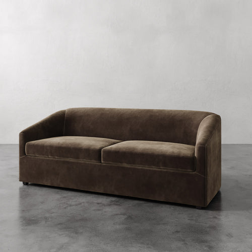Lemieux et Cie Arvelle Queen Sleeper sofa in warm taupe, low-profile form with rounded arms, shown on polished concrete floor against neutral walls.