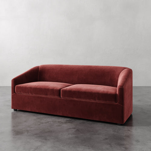 Lemieux et Cie Arvelle Queen Sleeper in warm terracotta velvet, streamlined two-cushion sofa shown on polished concrete floor against neutral wall.