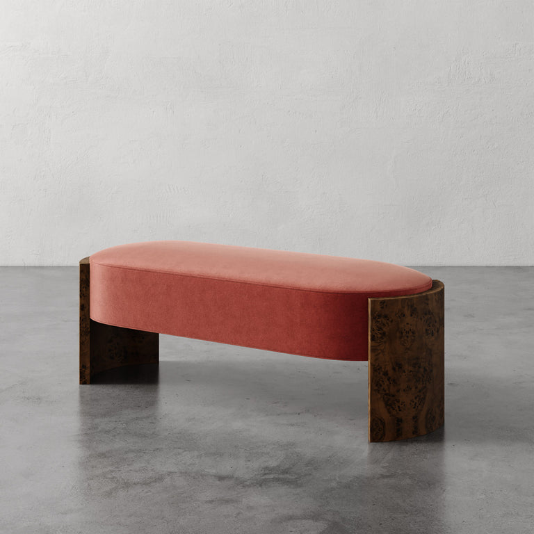 Lemieux et Cie Benoit Bench in blush velvet upholstery with curved Maple burl legs, low upholstered bench on polished concrete floor against textured plaster wall.