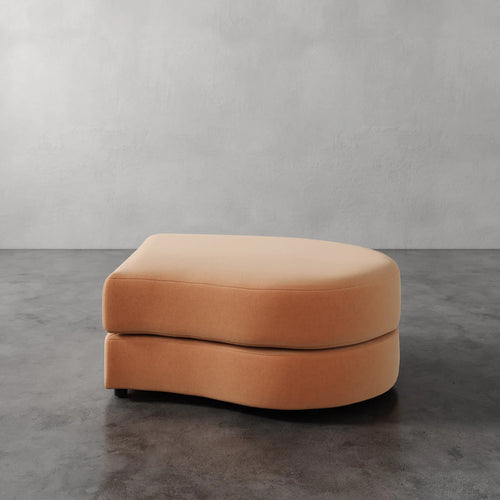 Lemieux Et Cie Rulmann Right Ottoman Orange ottoman on a gray floor with a plain gray wall background