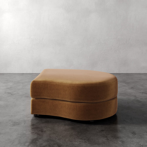 Lemieux Et Cie Rulmann Right Ottoman Brown ottoman on a gray concrete floor with a white wall background