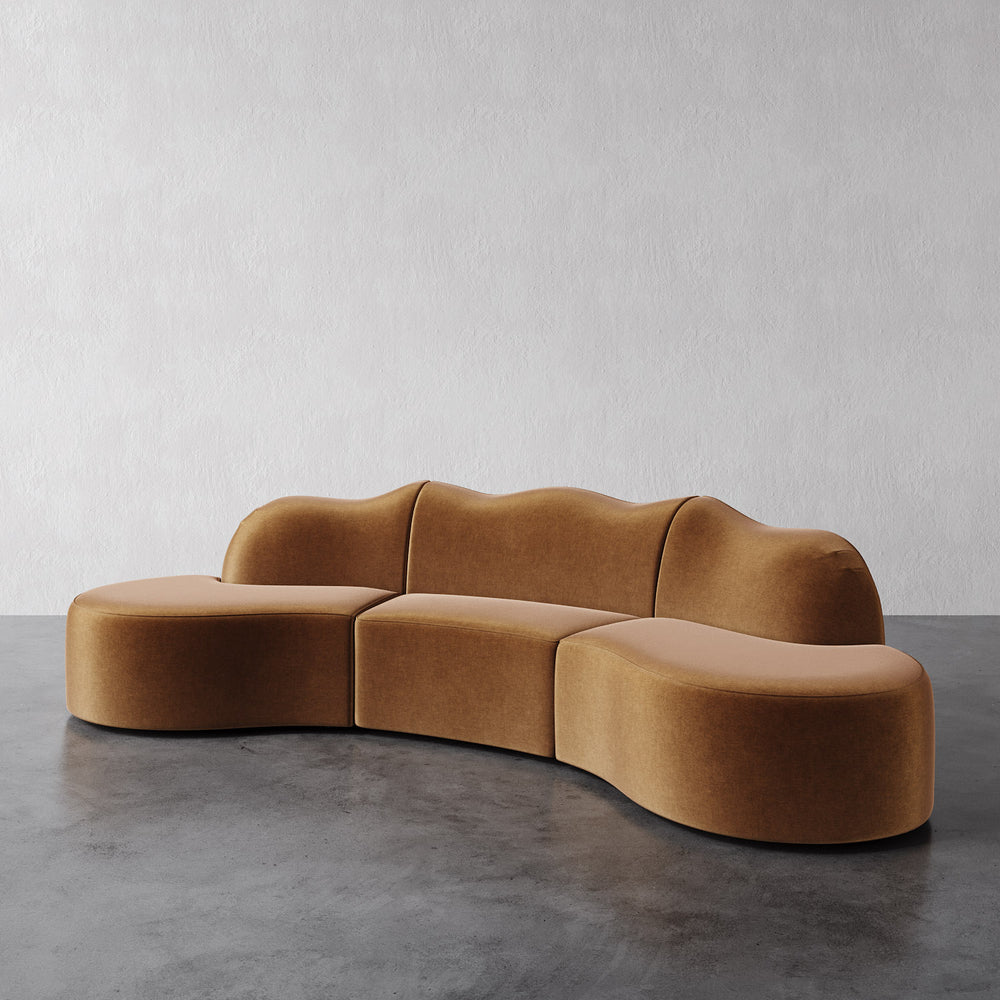 Lemieux et Cie Serpentine 3-Piece Sectional in warm caramel, organic curved modular sofa on polished concrete floor against textured plaster wall.