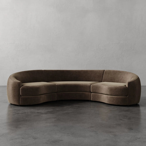 Lemieux Et Cie Rulmann Rulmann 3-Piece Sectional Brown curved sofa on a gray floor with a plain gray wall background