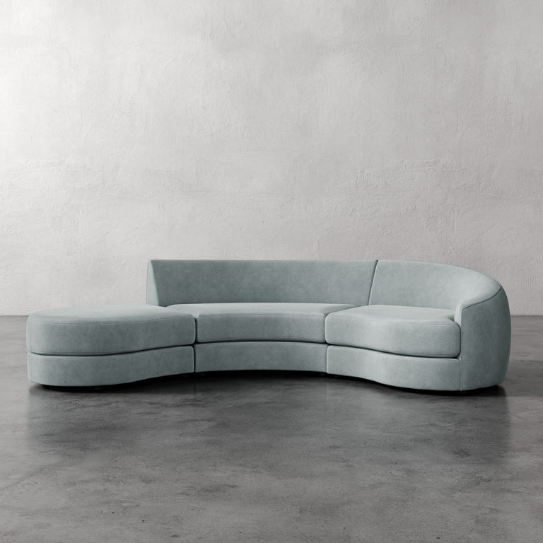 Lemieux Et Cie Rulmann 3-Piece Right Sectional  Modern curved sofa in a minimalistic setting with a plain wall and concrete floor.