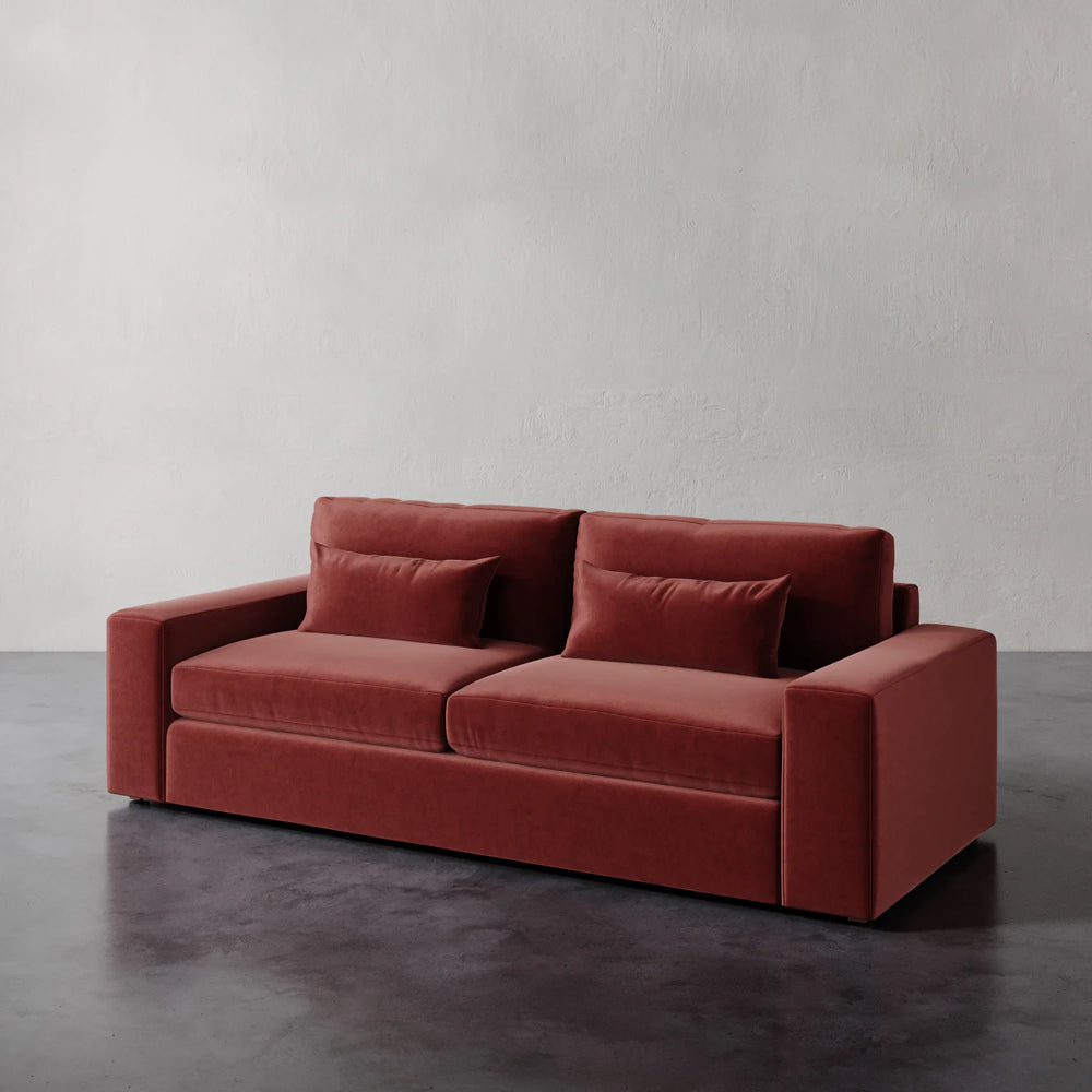 Lemieux et Cie Lacroix Sofa in terracotta, modular sofa with clean rectilinear lines, shown on dark concrete floor against textured plaster walls.