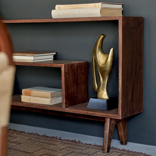 Lemieux et Cie Pierre Jeanneret bookcase in solid teak - styled three-quarter view showing the asymmetrical shelves with books and a brass bird sculpture