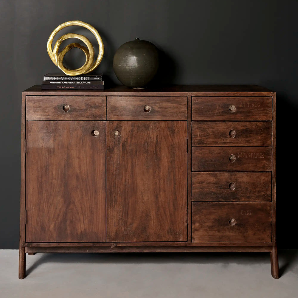 Lemieux et Cie Pierre Jeanneret library storage cabinet in solid teak - styled with a brass sculpture and a ceramic vessel on top against a dark wall