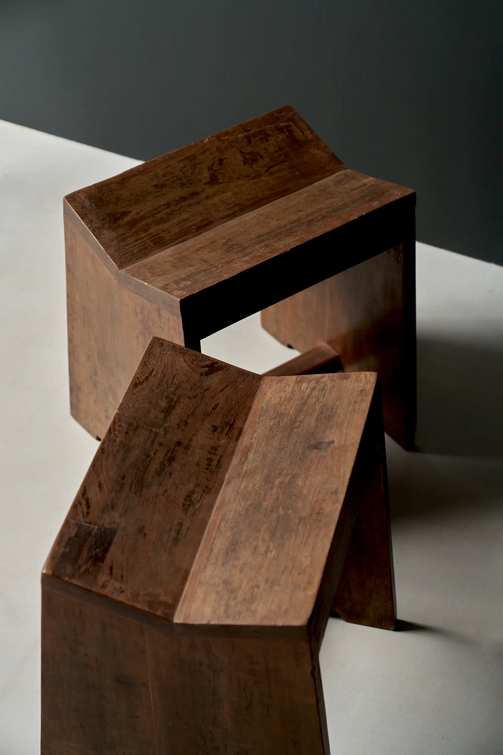 Lemieux et Cie Pierre Jeanneret stool in solid teak - two stools angled, showing the concave saddle seats and flat slab legs