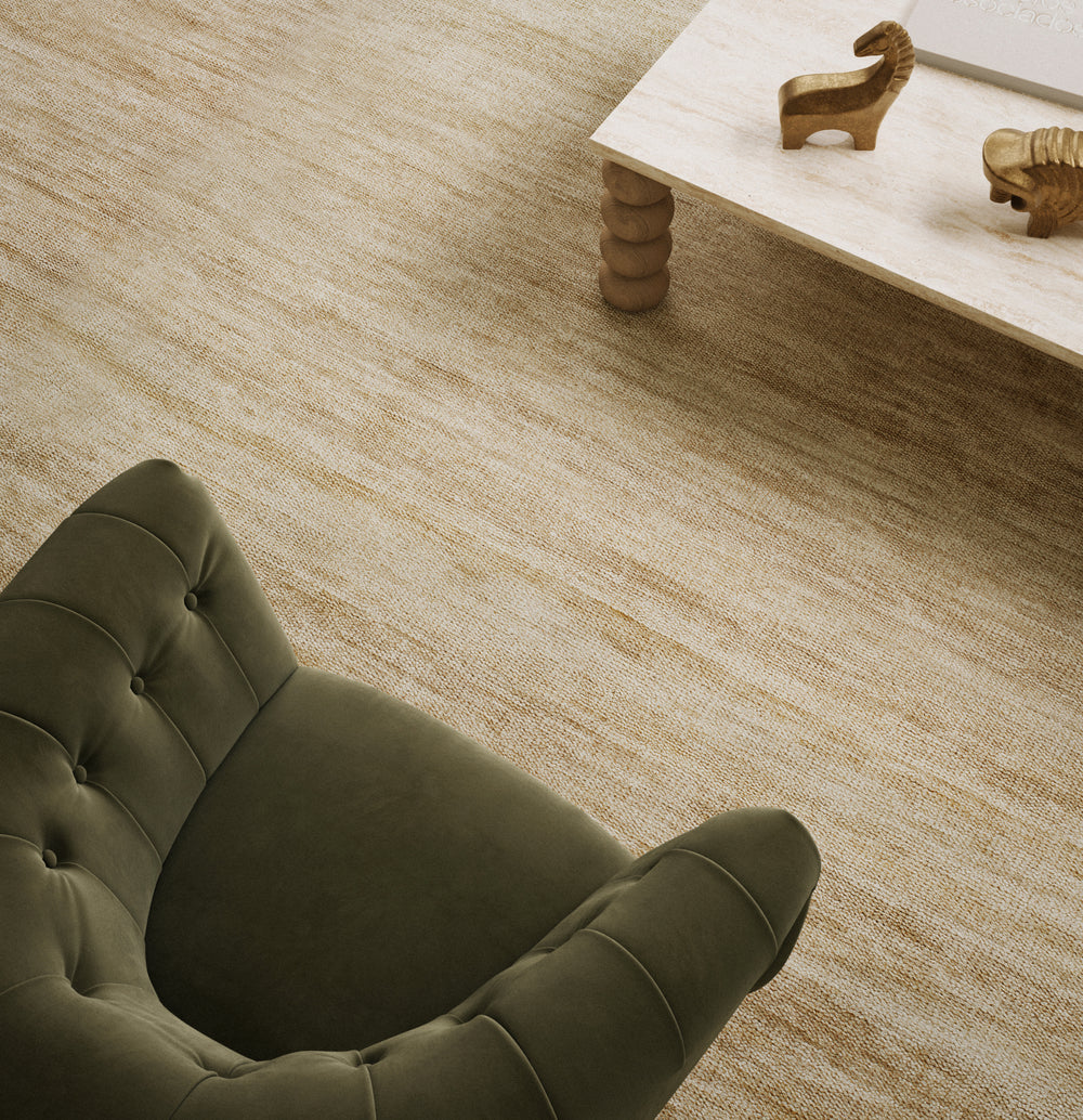 Lemieux et Cie Rochefort Handmade Wool Rug in flax, hand-knotted rug in warm neutral tones with olive tufted chair and stone table in soft daylight