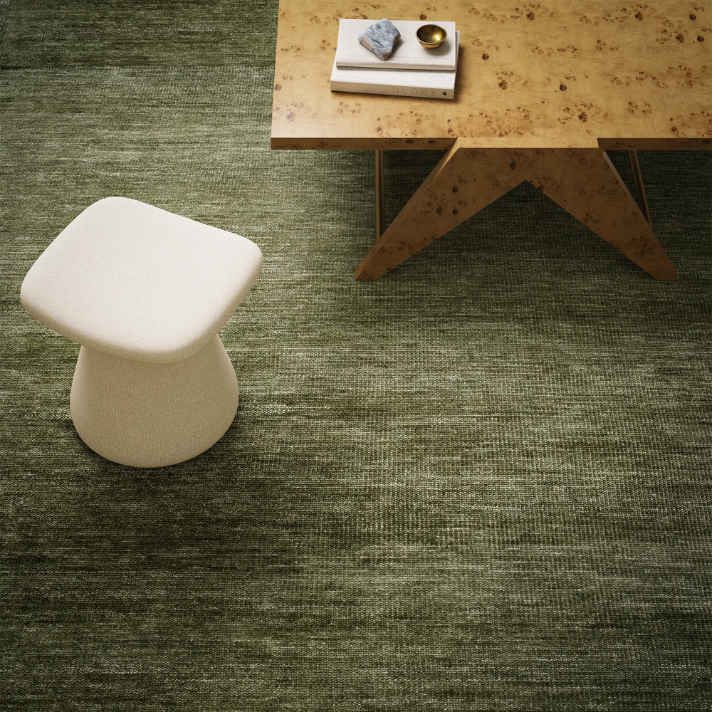 Lemieux et Cie Rochefort Handmade Wool Rug in olive green, woven floor rug with sculptural mushroom stool and low table on stone floor.