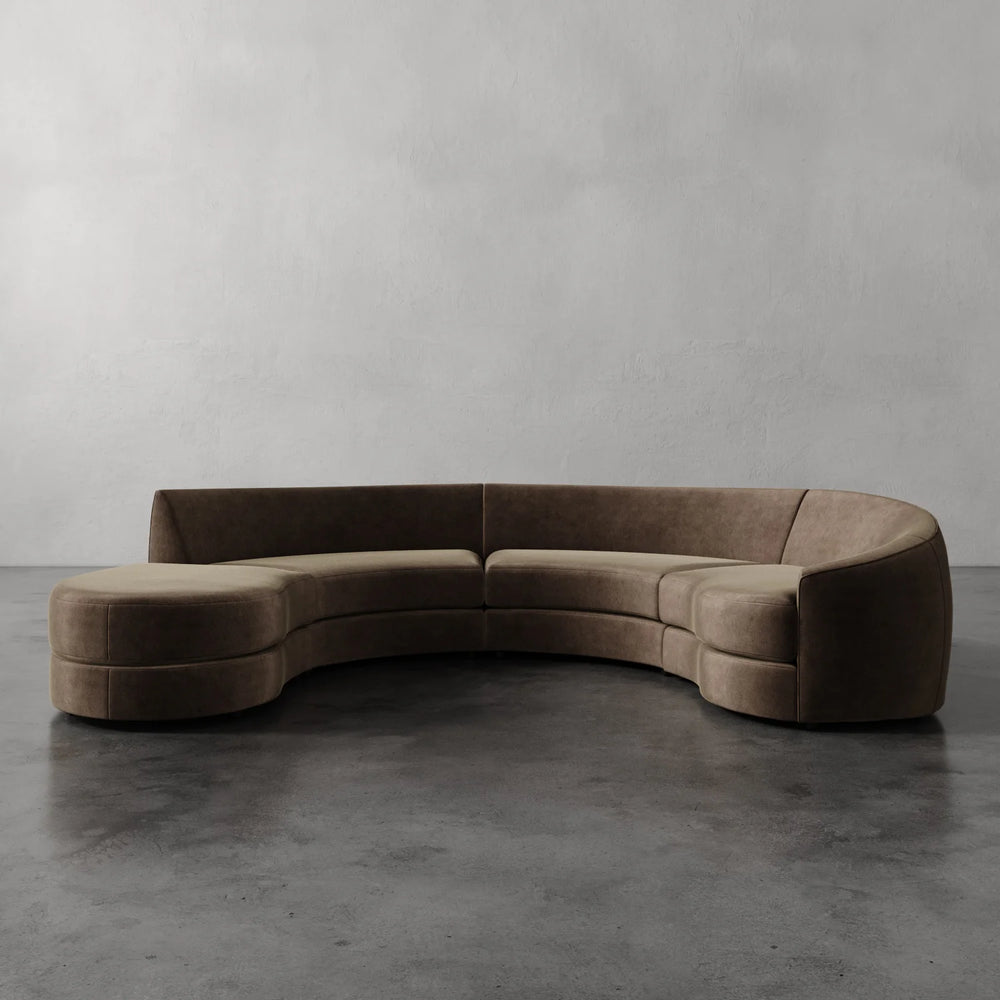Lemieux et Cie Rulmann 4-Piece Right Sectional, curved sectional sofa in warm taupe upholstery, shown on polished concrete floor against neutral plaster walls.