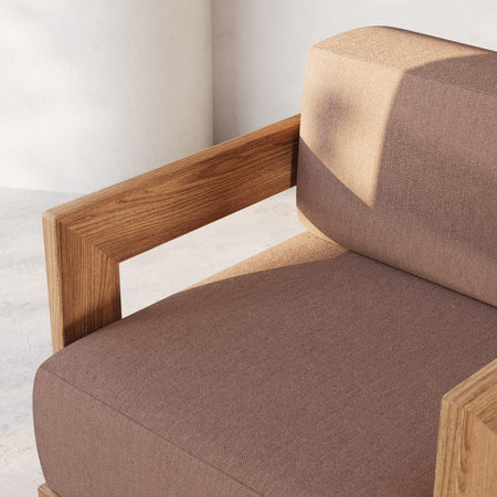 Lemieux et Cie S2 Teak Ottoman with solid teak frame and upholstered cushion in taupe and sand tones, shown on light concrete flooring against white walls.