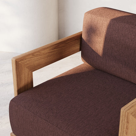 Lemieux et Cie S2 Teak Ottoman with solid teak frame and brown upholstered cushion, outdoor seating shown against white plaster walls.
