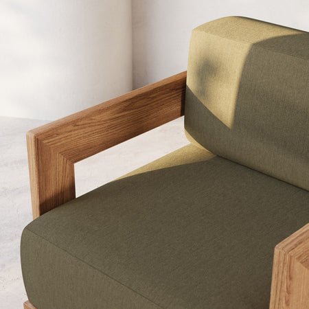 Lemieux et Cie S2 Teak Dining Arm Chair with angular frame and deep olive and sage cushions, shown against neutral plaster walls.