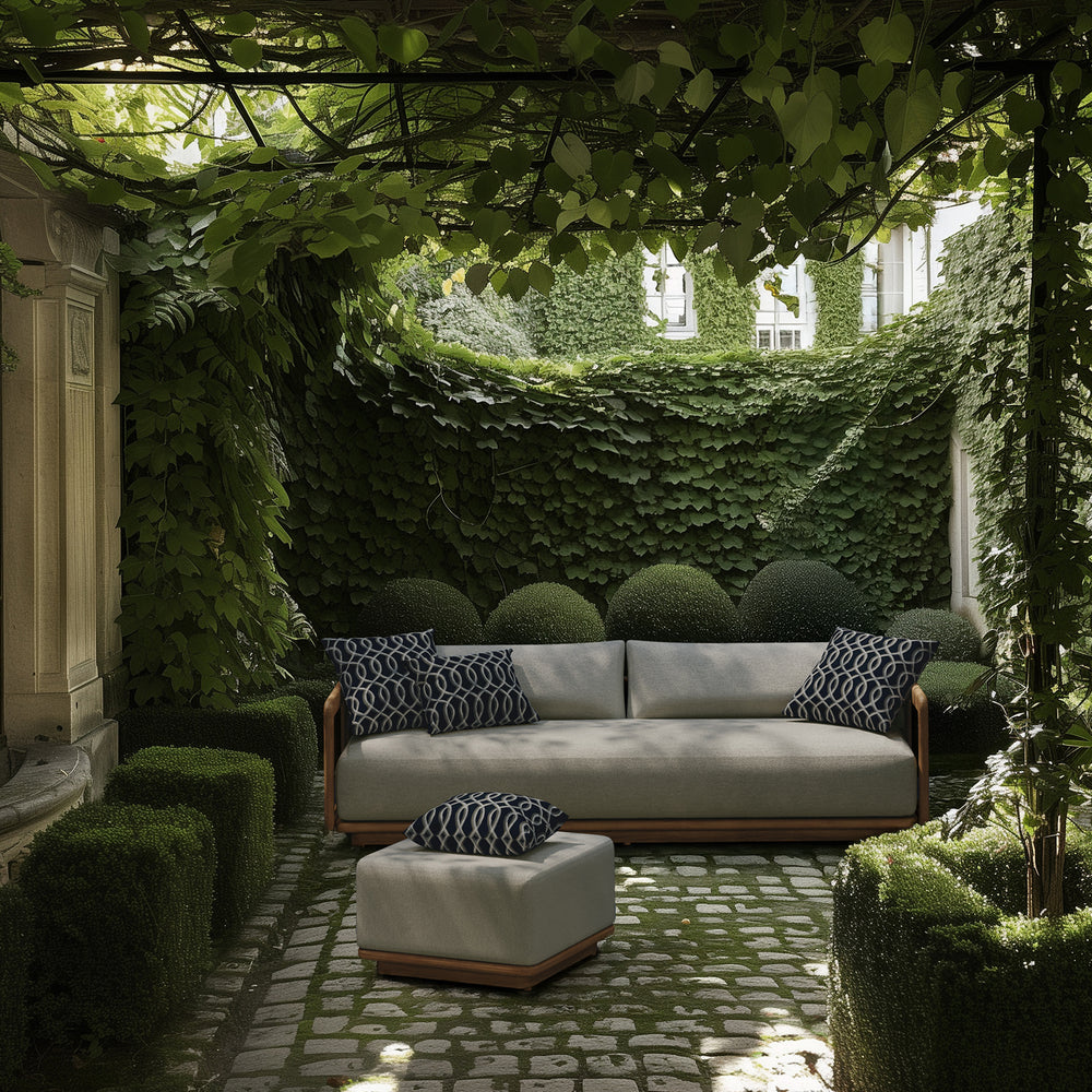 Lemieux et Cie Dock Teak 3-Seater Sofa with wood frame and neutral cushions, outdoor sofa in vine-covered courtyard with stone pavers and boxwood.