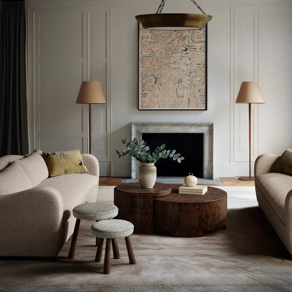 Lemieux et Cie Rondel Bunching Cocktail Table in walnut mappa burl, nested drum-form tables in a paneled living room with stone fireplace and light wood flooring.