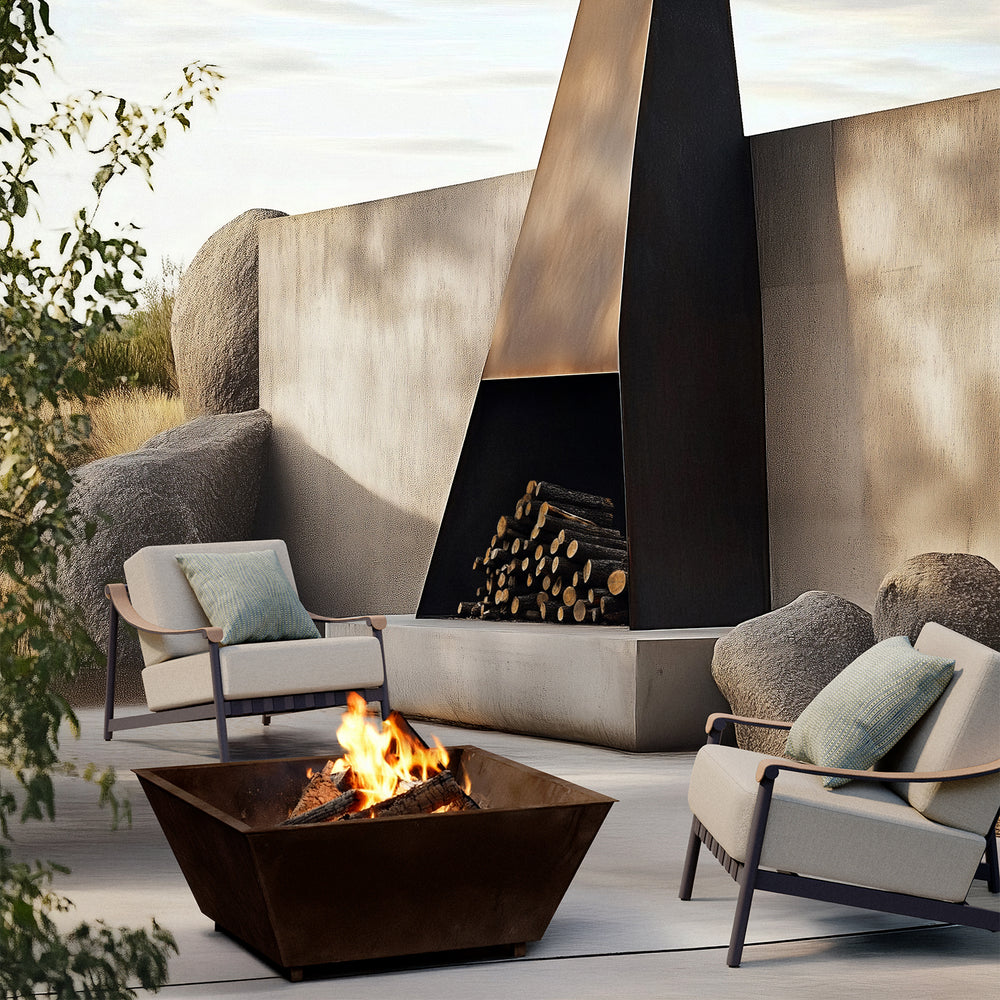 Lemieux et Cie Hudson Lounge Chair in ivory with blue accent pillow, sculptural outdoor seating flanking a fire pit on a patio terrace.