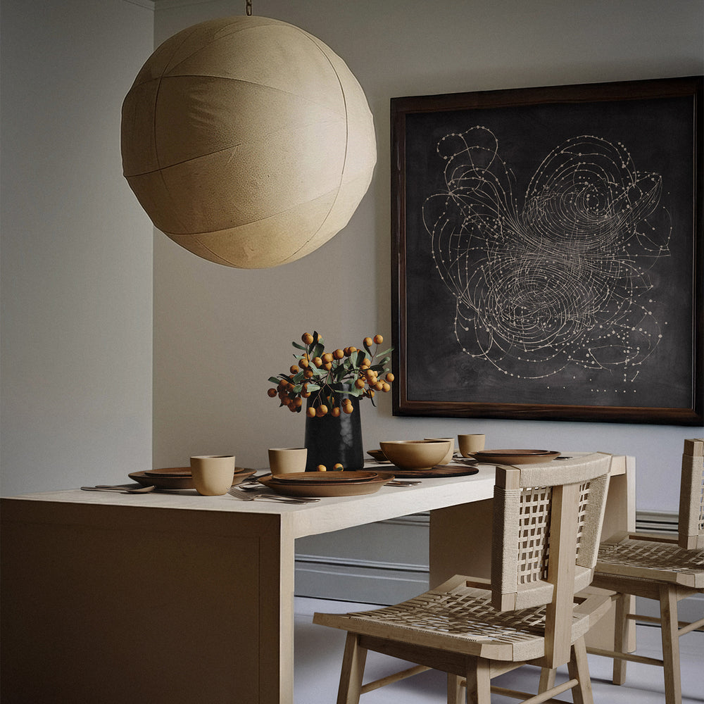 Lemieux et Cie Les Étoiles Limited Edition Art Print in dark framed presentation, hung above dining table with woven chairs in neutral-walled room.