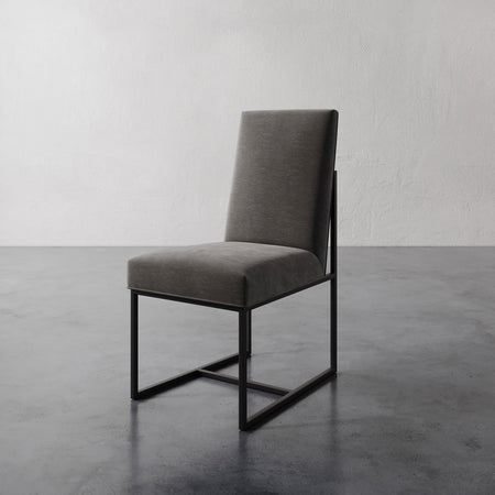 Lemieux et Cie Dupont Dining Side Chair with dark upholstered seat and backrest on structured frame, shown on polished concrete floor against white wall.