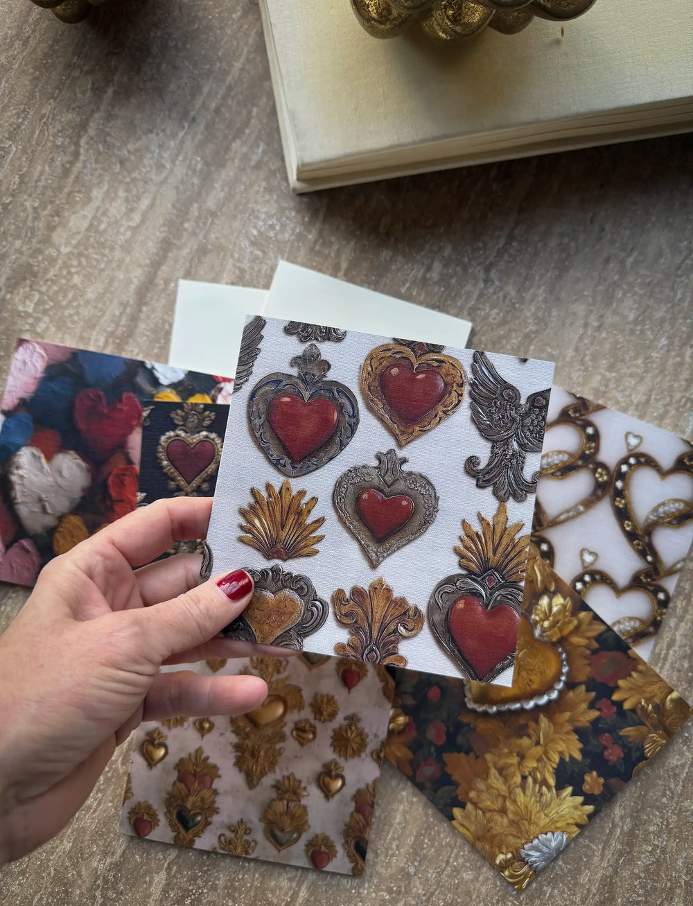 Lemieux et Cie Victorian Locket Greeting Card Set on linen paper, featuring ornate hearts and baroque motifs, shown with coordinating gift wrap on neutral stone surface.