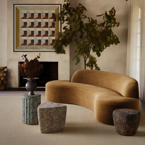 Modern living room with a brown curved sofa, decorative lemieux et cie reactive glaze stools, and a geometric art piece on the wall. Handmade for indoor and outdoor use. 