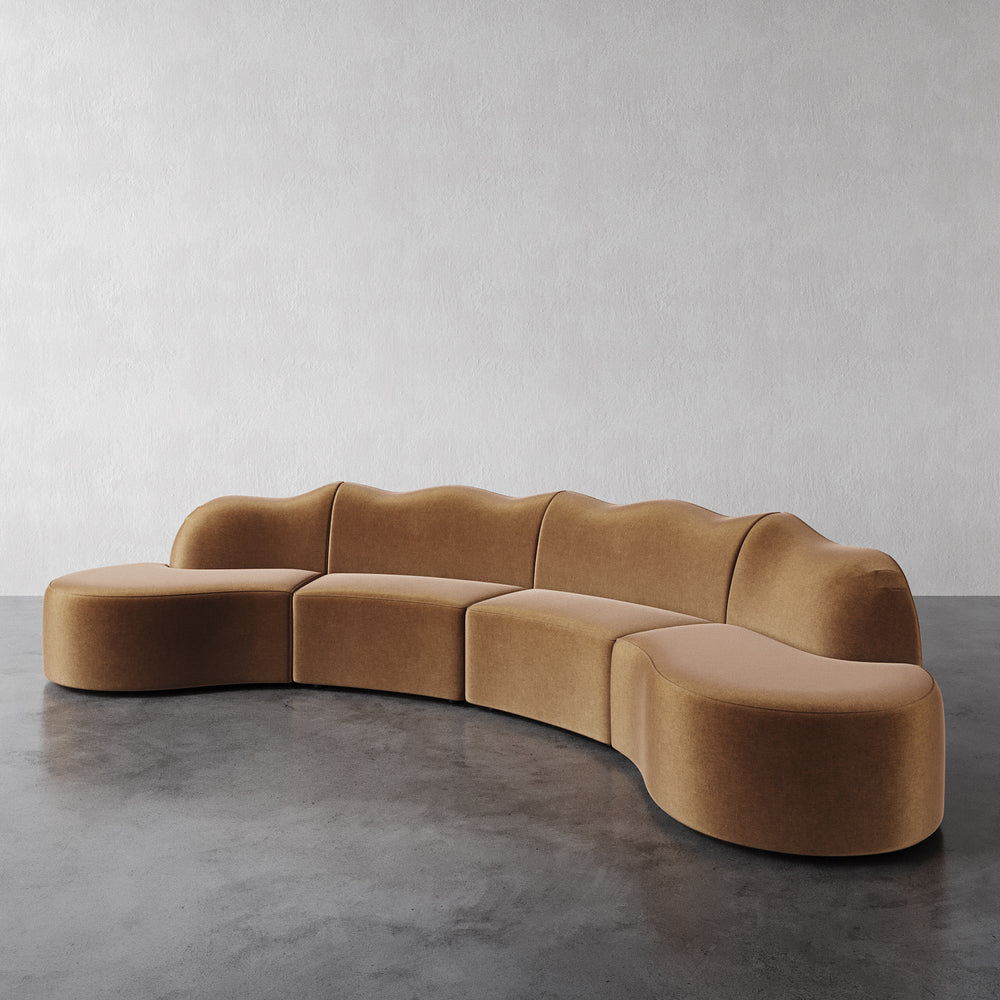 Lemieux et Cie Serpentine 4 Piece in nutmeg performance velvet, curved modular sectional sofa on polished concrete floor against white wall.
