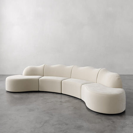 Lemieux et Cie Serpentine Sectional Sofa in ivory, modular curved sofa with organic rounded forms, shown on concrete floor against neutral plaster walls.