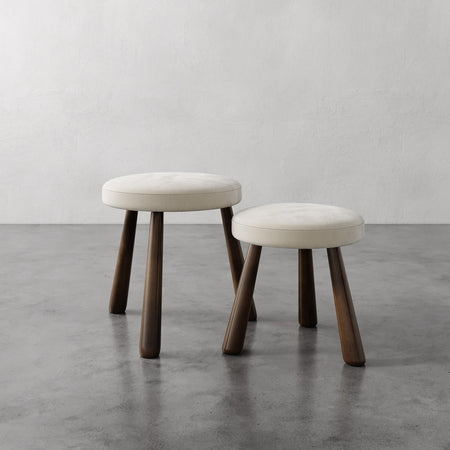 Lemieux et Cie Madeleine Stool with tapered legs and cushioned seat, two nesting stools on concrete floor against neutral plaster walls.