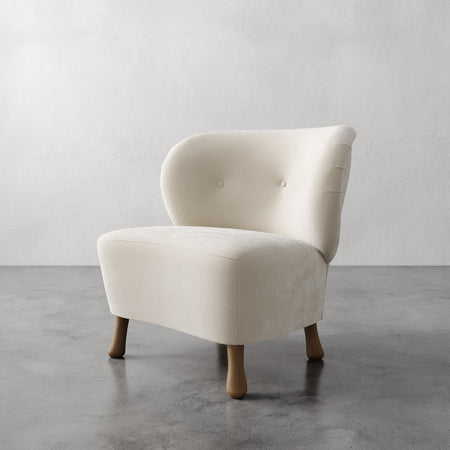Lemieux et Cie Tourenne Chair with sculptural turned legs, ivory upholstered slipper chair with button tufting, shown on polished concrete floor.