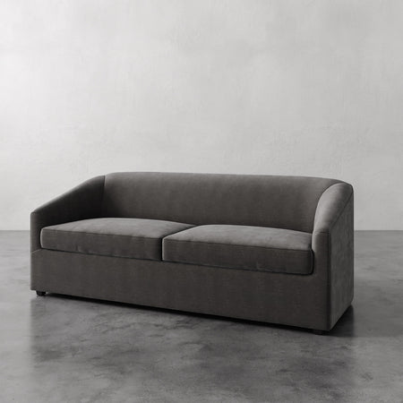 Lemieux et Cie Lemieux et Cia Arvelle Queen Sleeper in charcoal, sofa with curved arms and low profile, shown on concrete floor against neutral wall.