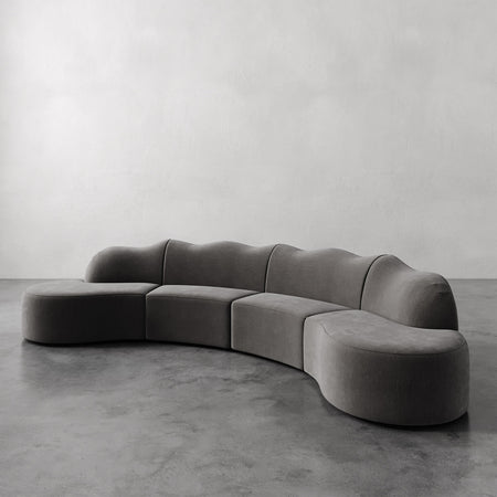 Lemieux et Cie Serpentine Sectional Sofa, curved modular form with rounded organic silhouette, shown on concrete floor in minimal room with neutral walls.