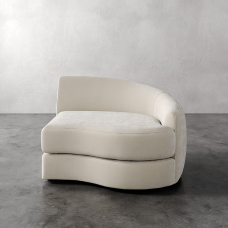 Lemieux et Cie Rulmann Right Arm Chair in ivory, curved sectional module on polished concrete floor against textured plaster walls.
