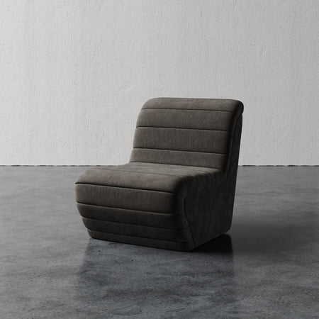 Lemieux et Cie Brunoy Chair, sculptural low-profile slipper chair with horizontal channel detailing, shown on polished concrete floor against textured white plaster walls.